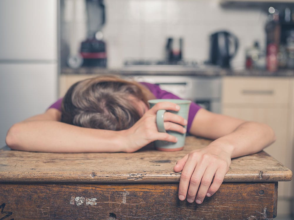 A sleeping woman holding a coffee cup