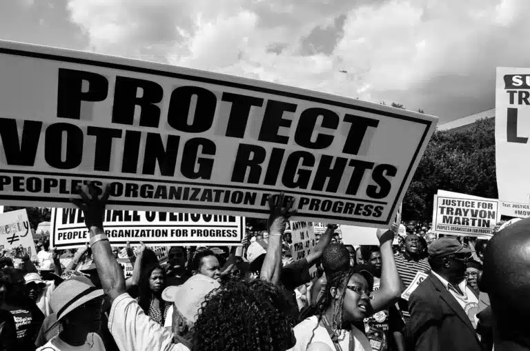 Crowd of protesters holding signs that read 'Protect Voting Rights' at a civil rights demonstration.